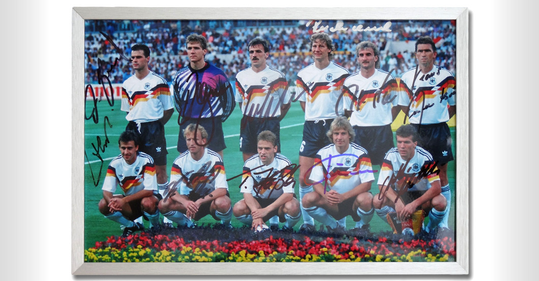 Die 1990er Weltmeister um Lothar Matthäus signieren ein Foto